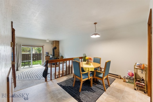 dining area featuring a baseboard radiator, a wood stove, and a textured ceiling