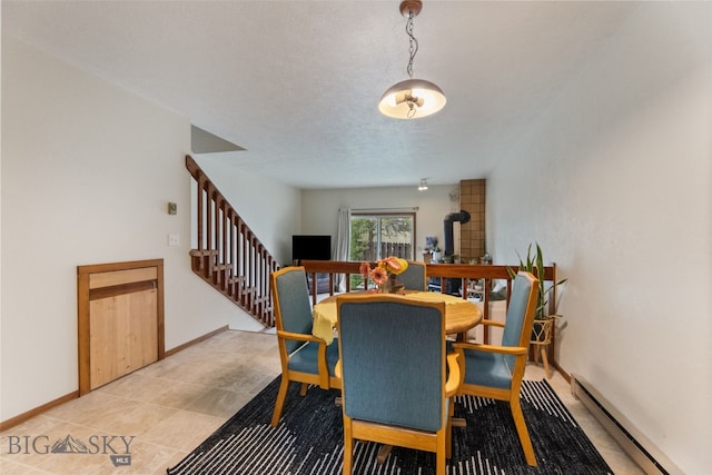 dining area with baseboard heating, stairway, a wood stove, and baseboards