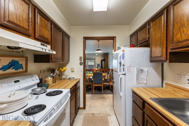 kitchen featuring electric stove, under cabinet range hood, light tile patterned flooring, and a wood stove