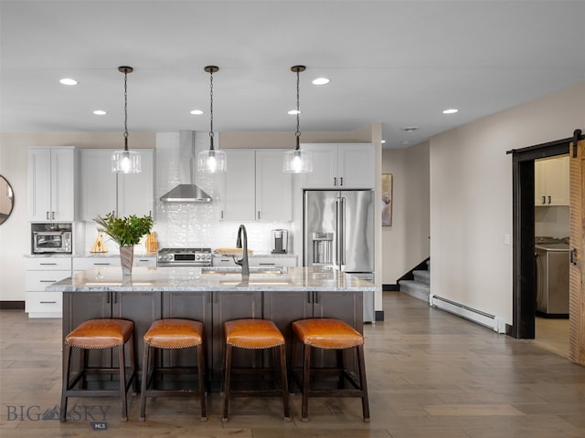 449 Minni Hall Rd, Bozeman, MT 59715 - kitchen with wall chimney exhaust hood, a baseboard heating unit, washer / dryer, a sink, and a center island with sink