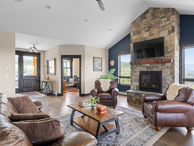 449 Minni Hall Rd, Bozeman, MT 59715 - living room featuring vaulted ceiling, healthy amount of natural light, wood finished floors, a stone fireplace, and baseboard heating