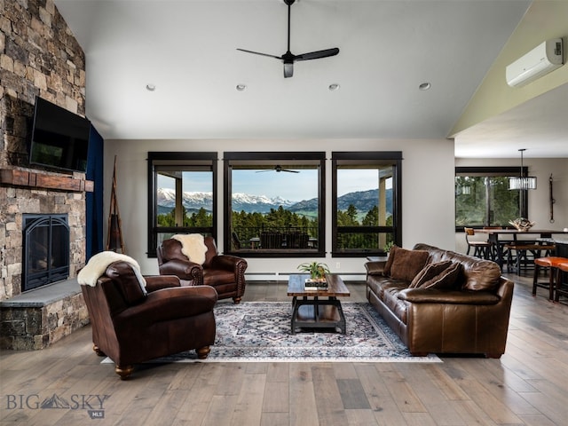 449 Minni Hall Rd, Bozeman, MT 59715 - living area featuring a ceiling fan, a stone fireplace, a mountain view, a wall mounted AC, and high vaulted ceiling