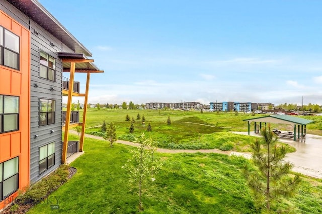 view of green lawn featuring a balcony