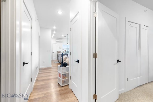 corridor with a wall mounted air conditioner, light wood-type flooring, recessed lighting, and baseboards