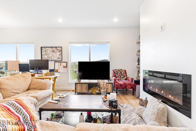 living room featuring wood finished floors, a glass covered fireplace, and recessed lighting