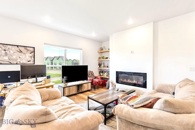 living room with a glass covered fireplace, light wood finished floors, and recessed lighting
