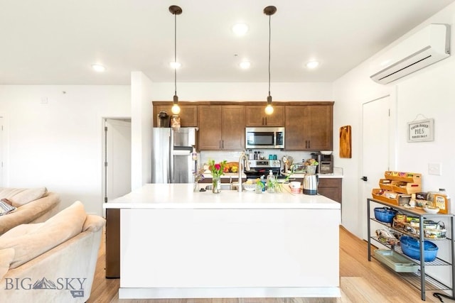 kitchen featuring stainless steel appliances, an AC wall unit, light countertops, open floor plan, and light wood-style floors