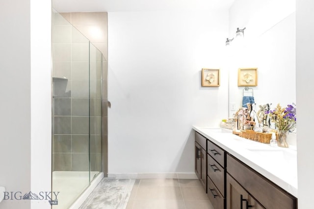 full bathroom with a shower stall, double vanity, tile patterned flooring, and baseboards