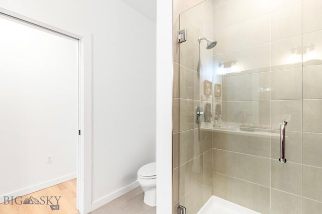 bathroom with a shower stall, toilet, and baseboards