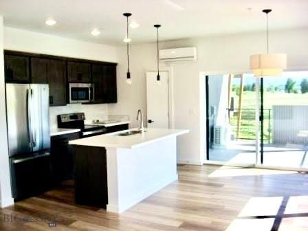 kitchen featuring stainless steel appliances, light wood-style flooring, light countertops, a wall mounted AC, and recessed lighting
