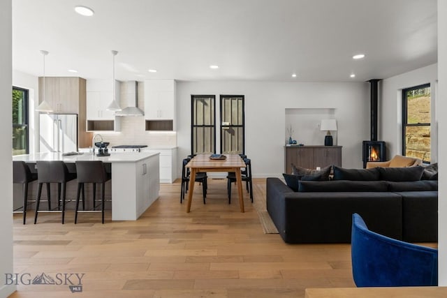 living area with light wood-type flooring, recessed lighting, and a wood stove