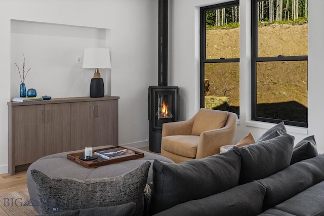 living area featuring a wood stove, baseboards, and light wood-style floors