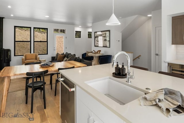 kitchen featuring a sink, light countertops, light wood finished floors, recessed lighting, and decorative light fixtures