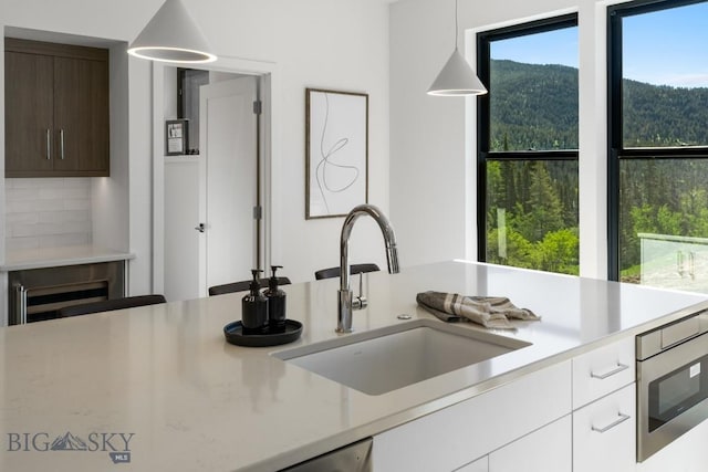 kitchen featuring a sink, light countertops, hanging light fixtures, and modern cabinets