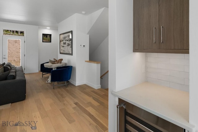 living room with beverage cooler, light wood-style floors, and baseboards