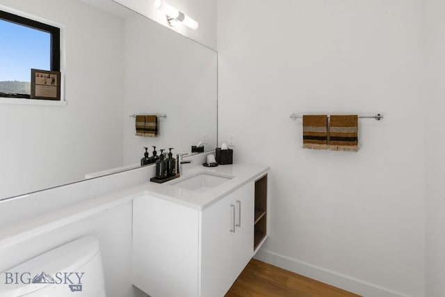 bathroom featuring baseboards, wood finished floors, vanity, and toilet
