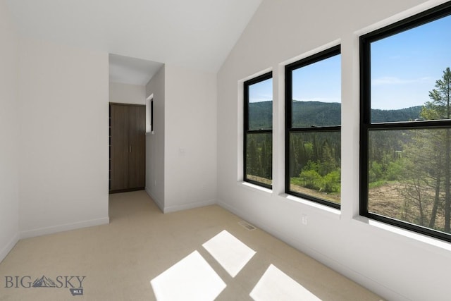 carpeted empty room featuring lofted ceiling and baseboards
