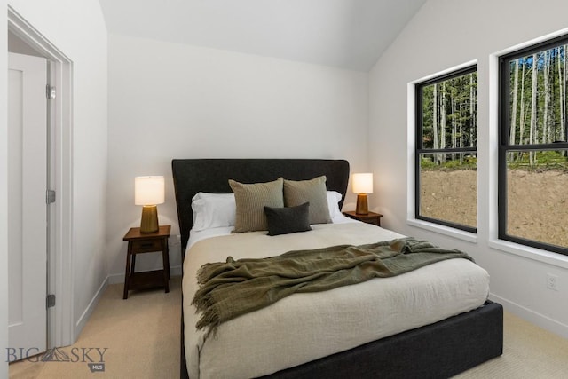 bedroom featuring light colored carpet, lofted ceiling, and baseboards