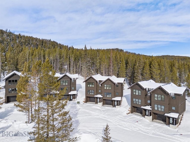 snowy aerial view with a wooded view