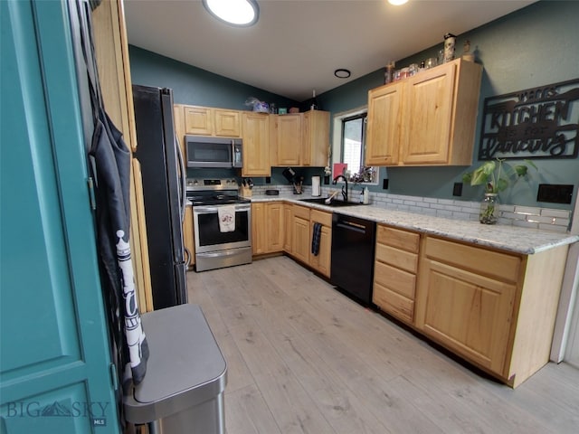 902 E Gallatin Ave, Belgrade, MT 59714 - kitchen with stainless steel appliances, light brown cabinetry, vaulted ceiling, a sink, and light wood-style floors