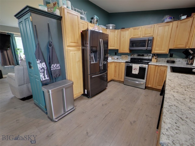 902 E Gallatin Ave, Belgrade, MT 59714 - kitchen with stainless steel appliances, light brown cabinetry, light wood finished floors, light stone counters, and a sink