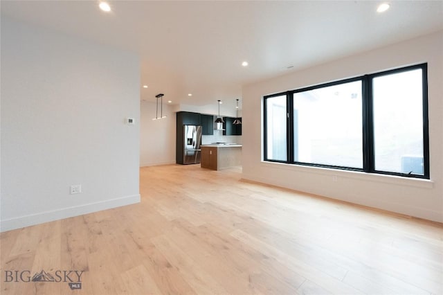 unfurnished living room with light wood finished floors, baseboards, and recessed lighting