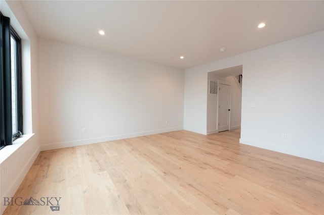 spare room featuring healthy amount of natural light, light wood-style floors, recessed lighting, and baseboards