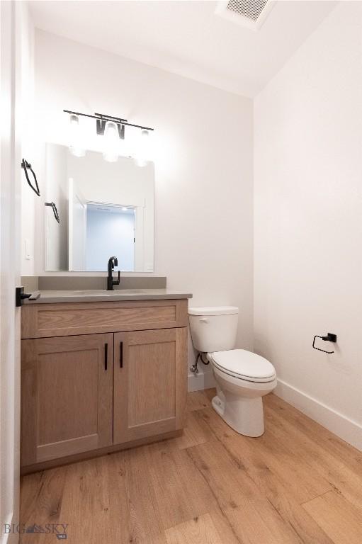 bathroom featuring toilet, wood finished floors, vanity, and baseboards