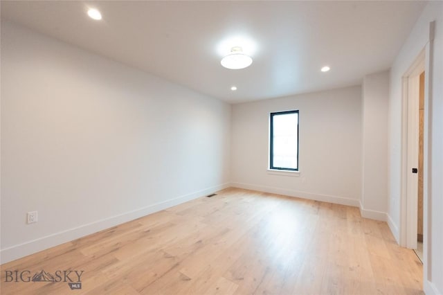 spare room featuring light wood finished floors, baseboards, and recessed lighting