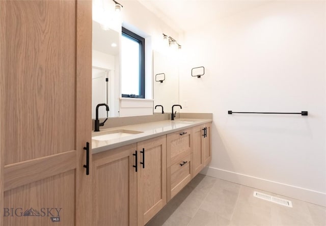 bathroom with double vanity, baseboards, and tile patterned flooring