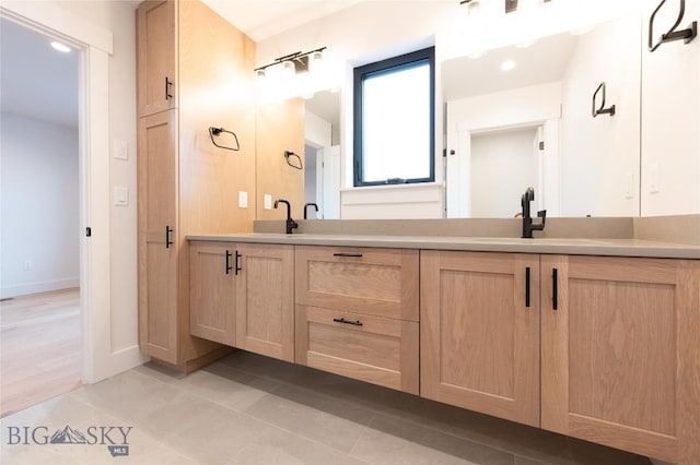 bathroom featuring double vanity, tile patterned floors, and baseboards