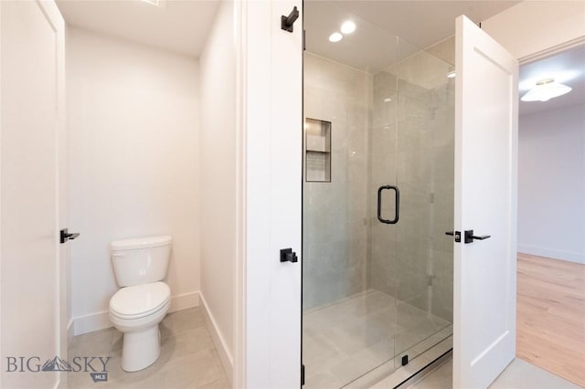 bathroom with toilet, baseboards, a stall shower, and tile patterned flooring