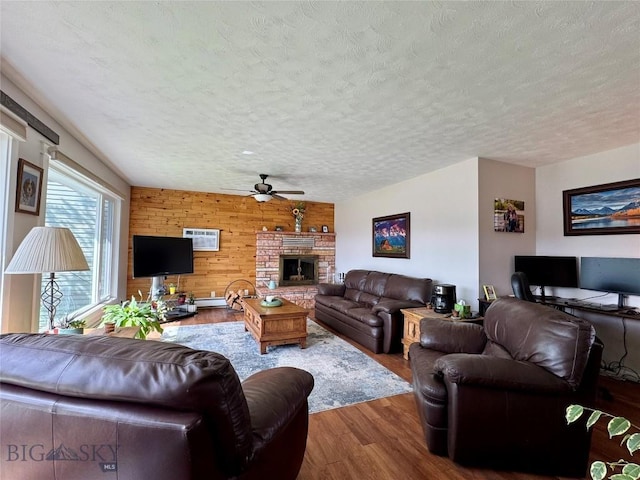 205 E Chinook St, Livingston, MT 59047 - living area with ceiling fan, wooden walls, wood finished floors, a textured ceiling, and a fireplace with raised hearth