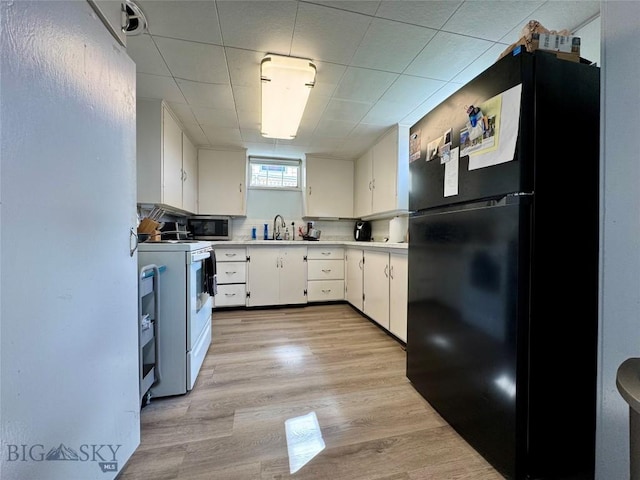 205 E Chinook St, Livingston, MT 59047 - kitchen with white electric stove, freestanding refrigerator, white cabinets, light countertops, and stainless steel microwave