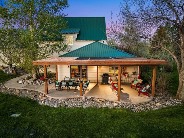 530 W Hulbert Rd, Bozeman, MT 59718 - back of house at dusk with a lawn, a patio area, metal roof, and a standing seam roof