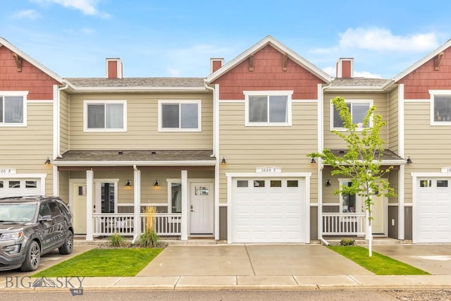 townhome / multi-family property with covered porch, driveway, an attached garage, and roof with shingles