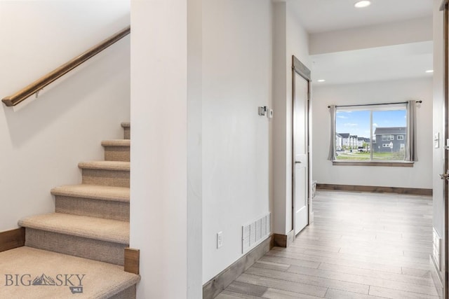 stairs with wood finished floors, recessed lighting, and baseboards