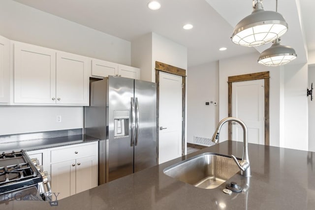 kitchen with stainless steel appliances, a sink, dark countertops, recessed lighting, and white cabinets