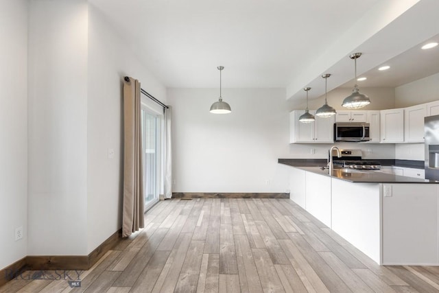 kitchen featuring appliances with stainless steel finishes, dark countertops, light wood-style floors, white cabinets, and recessed lighting