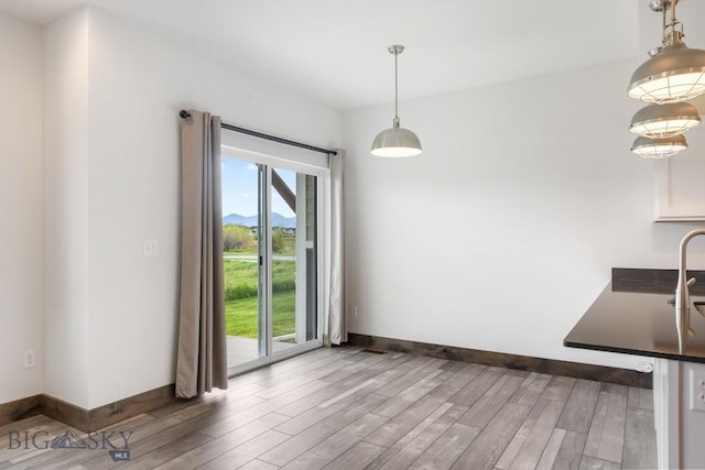 unfurnished dining area featuring wood finished floors and baseboards