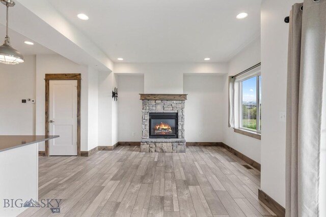 unfurnished living room with light wood-type flooring, baseboards, a fireplace, and recessed lighting