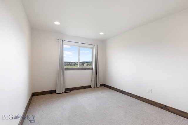 spare room featuring light carpet, recessed lighting, and baseboards