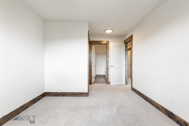 unfurnished room featuring carpet floors, baseboards, and a smoke detector