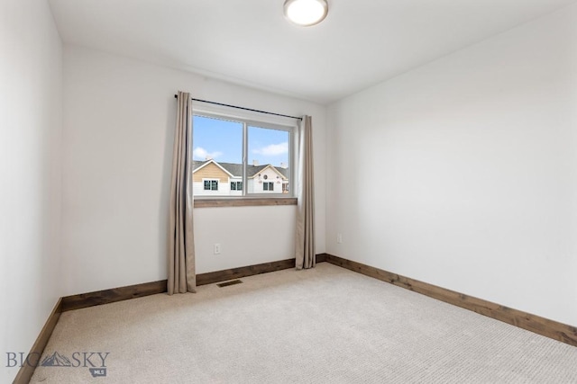 spare room featuring light carpet and baseboards