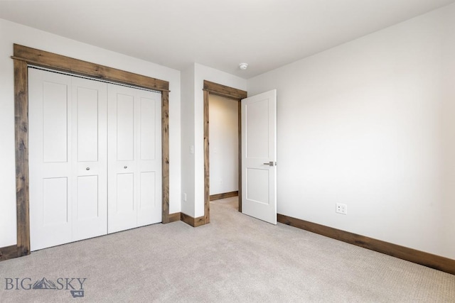 unfurnished bedroom featuring carpet, baseboards, and a closet