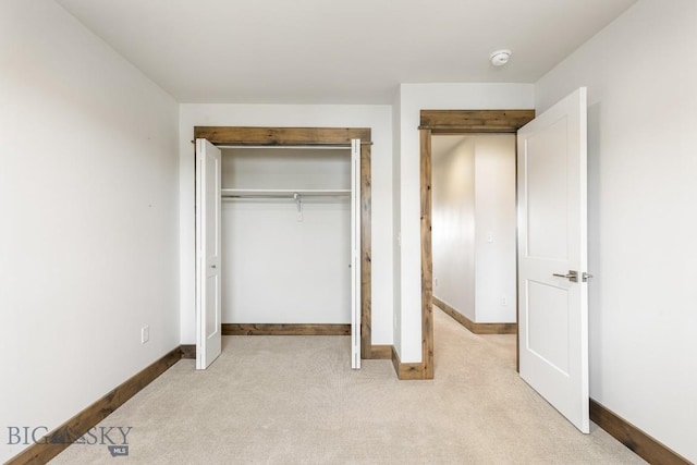 unfurnished bedroom featuring carpet, baseboards, and a closet