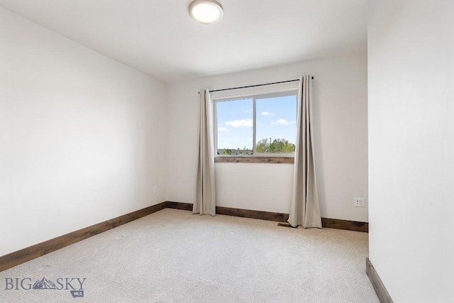 unfurnished room with light colored carpet and baseboards