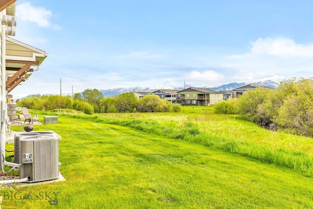 view of green lawn featuring central AC unit and a mountain view