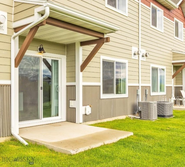 rear view of property featuring a patio, a lawn, and central AC