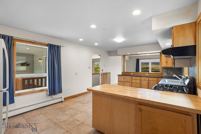 601 N C St, Livingston, MT 59047 - kitchen featuring wood counters, a peninsula, baseboard heating, baseboards, and under cabinet range hood